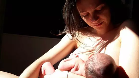 Mãe segurando e sentindo o cheiro de seu bebê recém-nascido durante o pós-parto